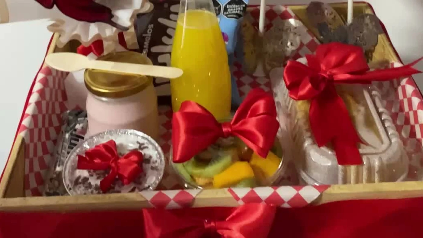 Bandeja de desayuno sorpresa con jugo de naranja, yogurt, fruta fresca y repostería sobre mantel de cuadros, Detalles de Amor Medellín
