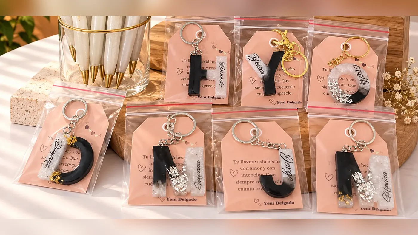 Siete llaveros de resina negra y blanca con la inicial y el nombre de cada persona, empacados uno por uno con tarjeta de mensaje, Detalles de Amor Medellín