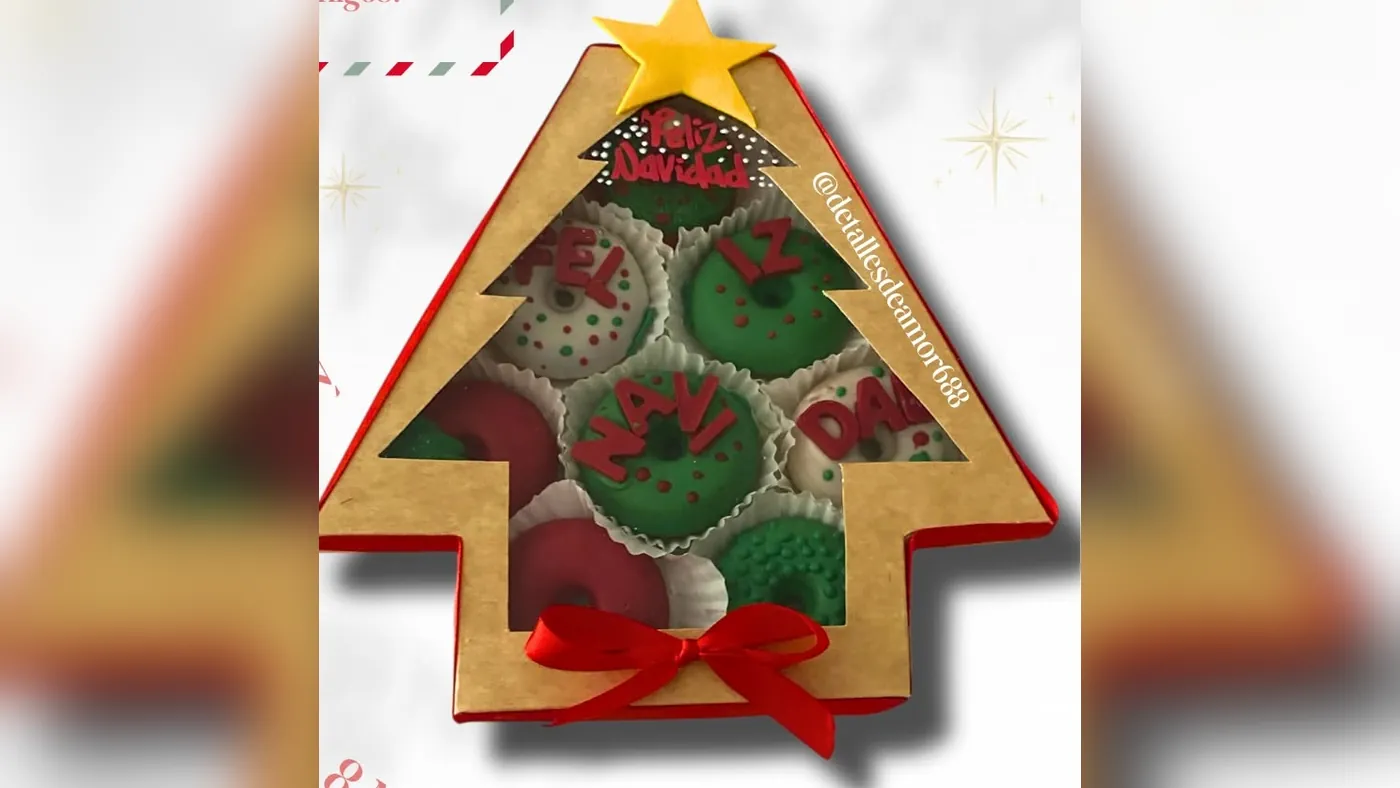 Caja en forma de árbol de Navidad con ocho mini donas decoradas en rojo, verde y blanco con letras de chocolate que forman Feliz Navidad, Detalles de Amor Medellín