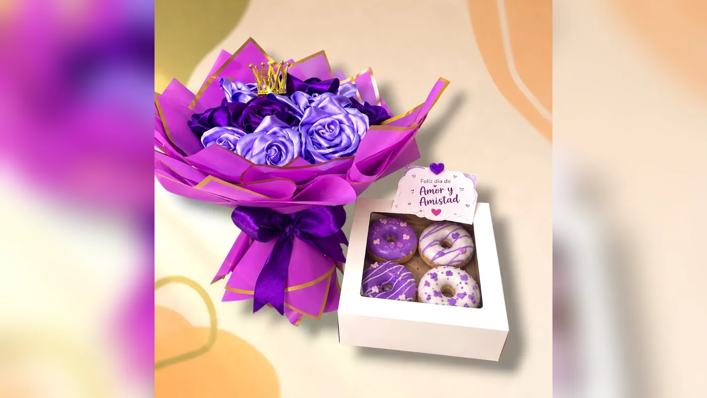 Ramo buchón de rosas eternas moradas y lila con corona dorada, junto a una caja de cuatro donas decoradas en morado con tarjeta de Amor y Amistad, Detalles de Amor Medellín