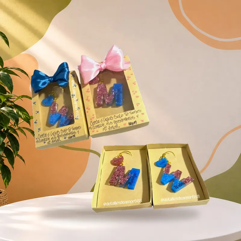 Cajitas de regalo con moño de satín, cada una con una pieza de resina personalizada con la letra y el nombre, Detalles de Amor Medellín