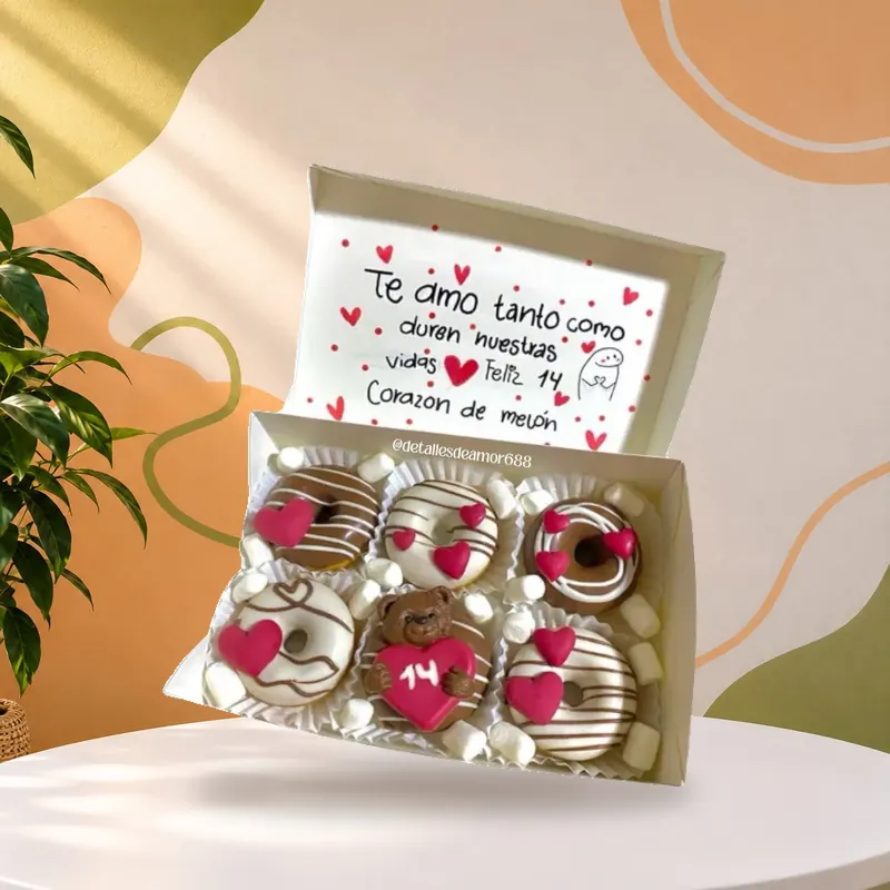 Caja de donas decoradas con tarjeta escrita a mano, del tipo que se usa como premio de aguinaldo